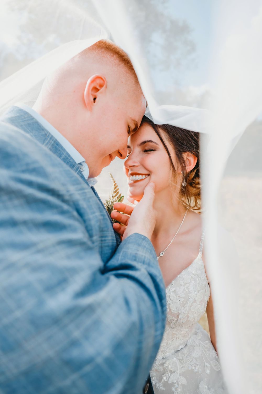 A tender moment between newlyweds sharing an intimate embrace outdoors on their wedding day.