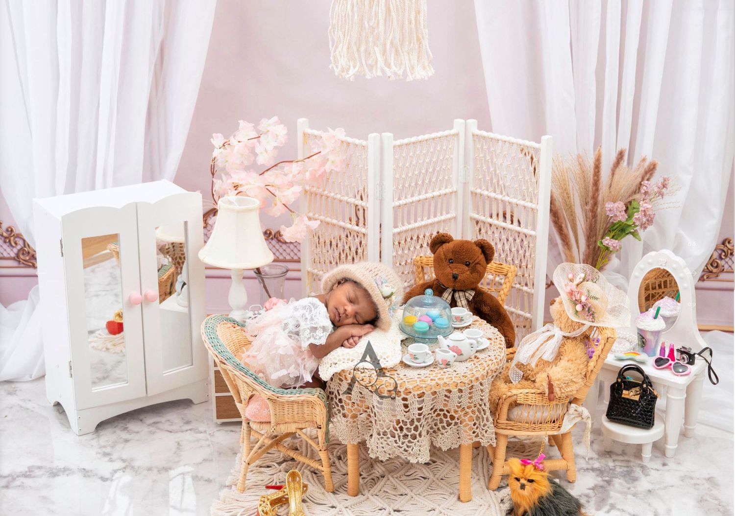 Elegant tea party themed photo setup with miniature furniture and soft white draping.