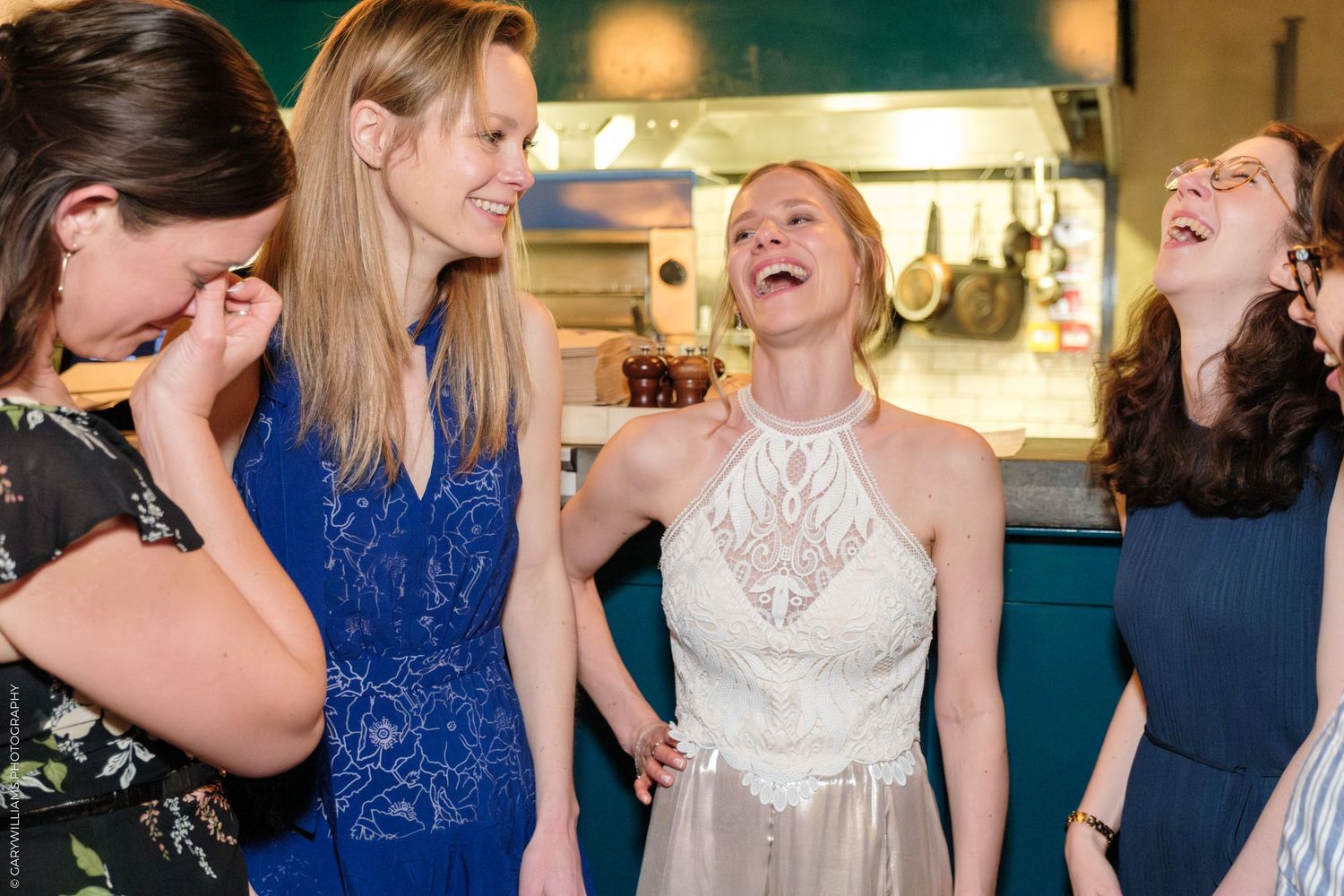 Four friends share a moment of uncontrollable laughter together at a social gathering.