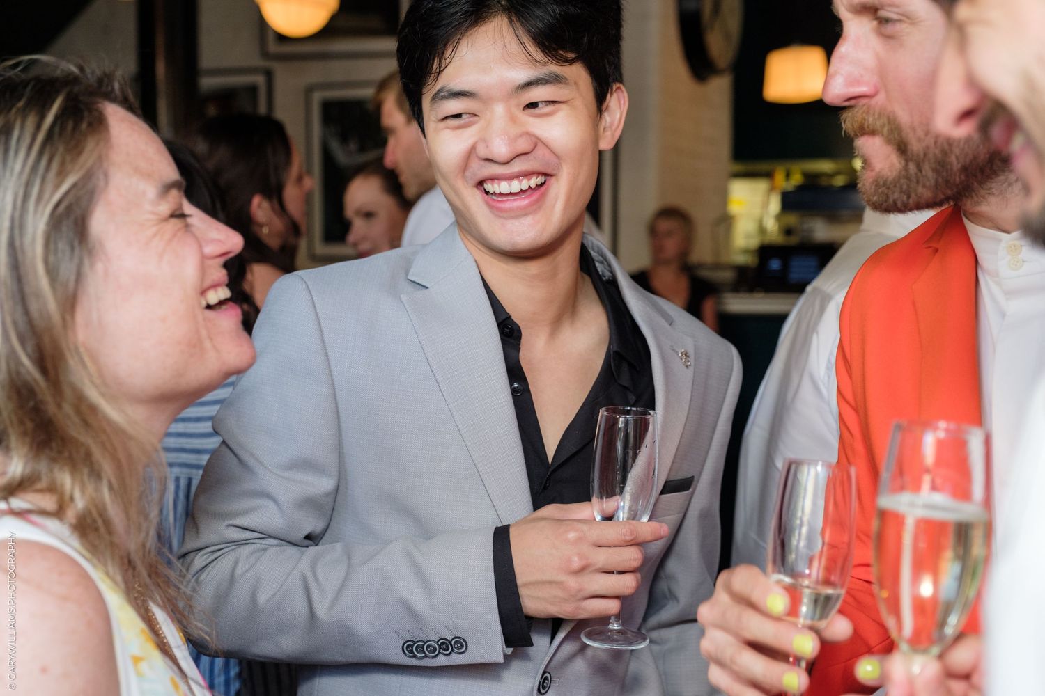 Friends laughing and socializing at a party while holding champagne glasses.