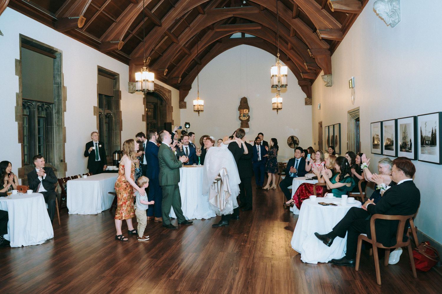 Wedding reception in elegant hall with vaulted wooden ceiling and guests enjoying celebration.