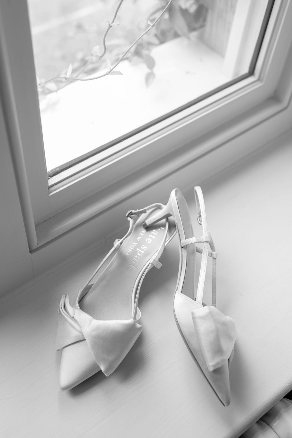 Sequence of white origami paper cranes arranged along windowsill in monochromatic lighting.
