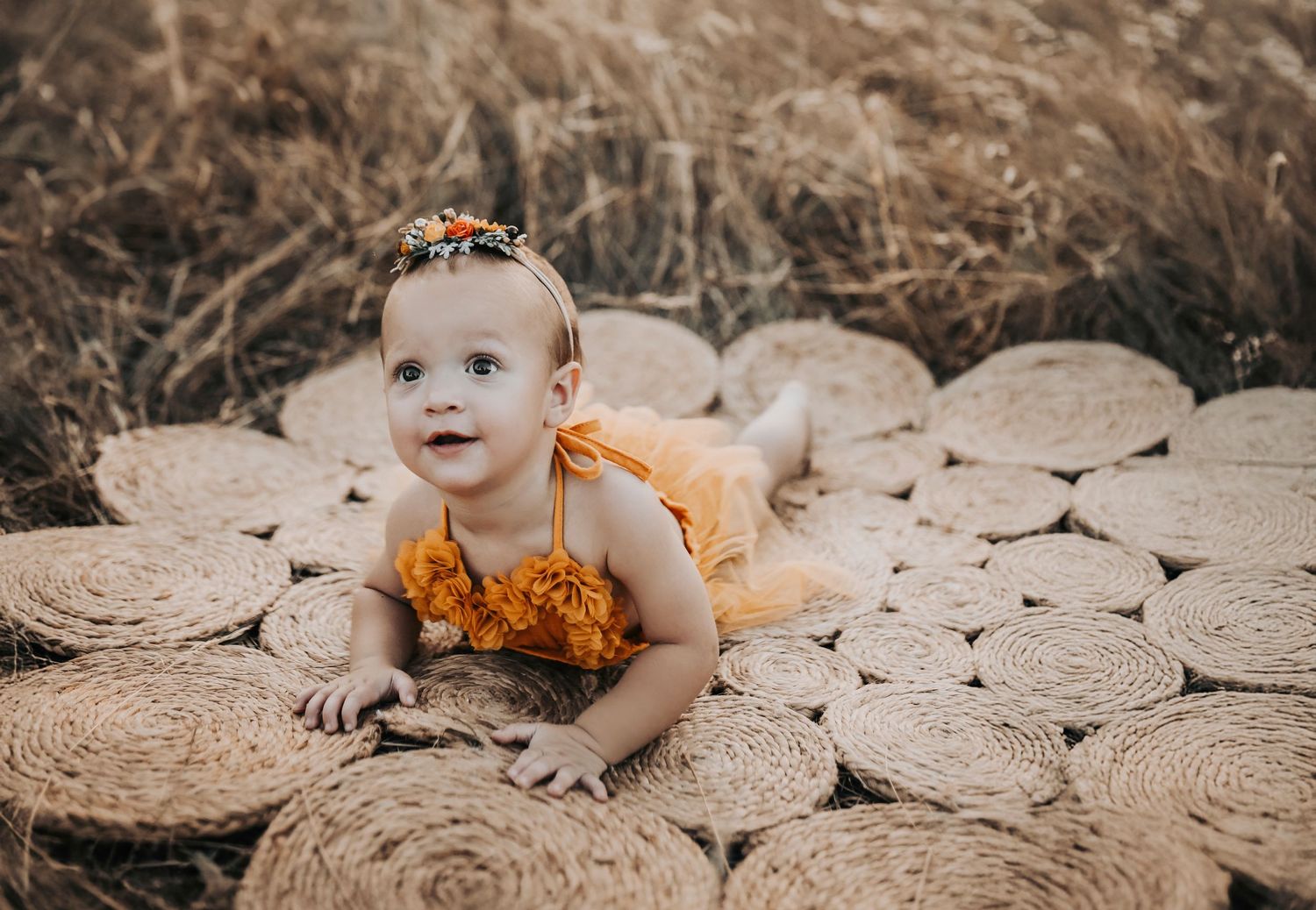 a super sweet one year old girls plays on her belly on top of a natural fiber rug