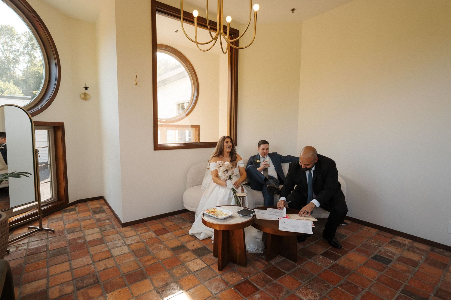 People gathered in a rustic room with terracotta floors and arched doorways for an intimate event.
