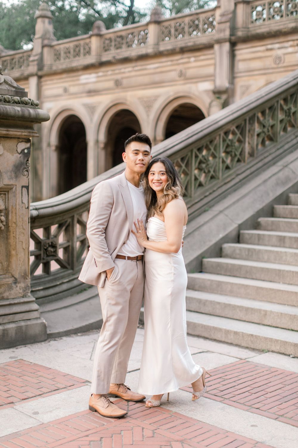 Engaged couple sharing a romantic moment by the iconic Bethesda Fountain in NYC.