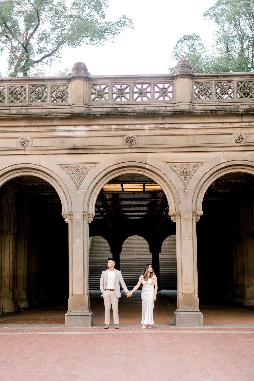 Engaged couple sharing a romantic moment by the iconic Bethesda Fountain in NYC.