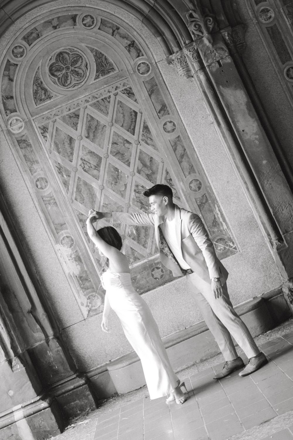 Engaged couple sharing a romantic moment by the iconic Bethesda Fountain in NYC.