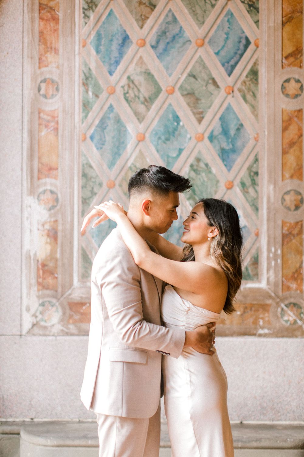 Engaged couple sharing a romantic moment by the iconic Bethesda Fountain in NYC.