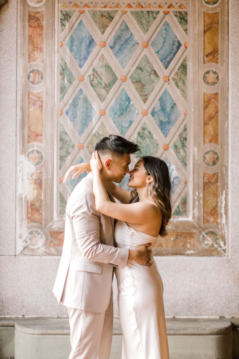 Engaged couple sharing a romantic moment by the iconic Bethesda Fountain in NYC.