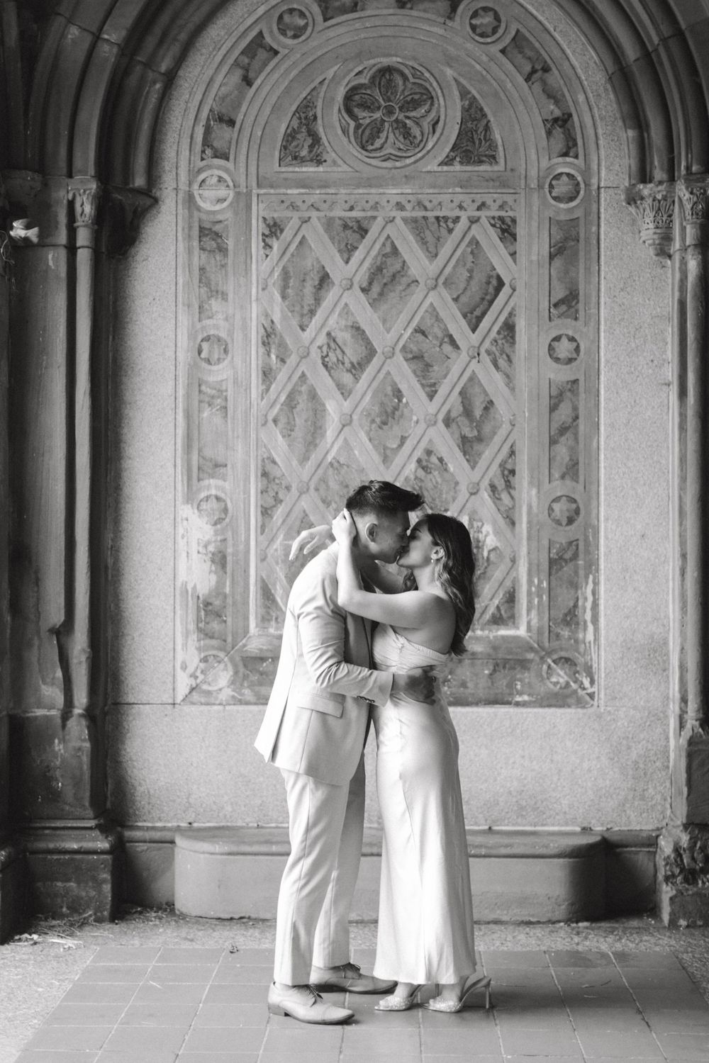 Engaged couple sharing a romantic moment by the iconic Bethesda Fountain in NYC.