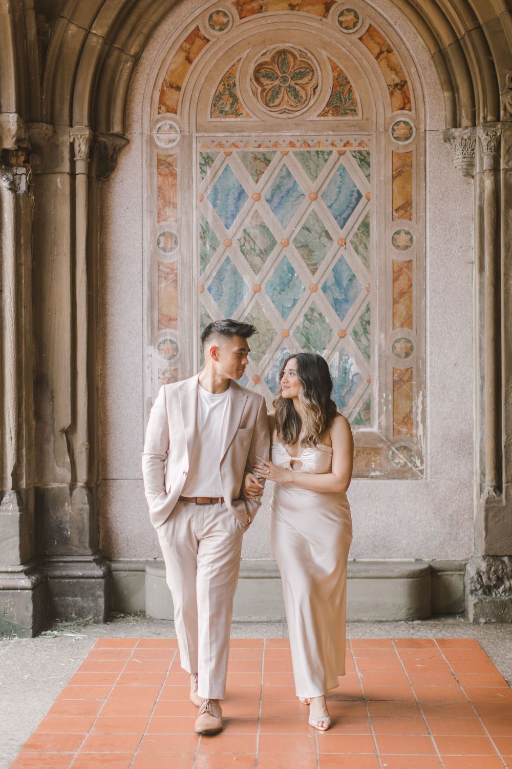 Engaged couple sharing a romantic moment by the iconic Bethesda Fountain in NYC.