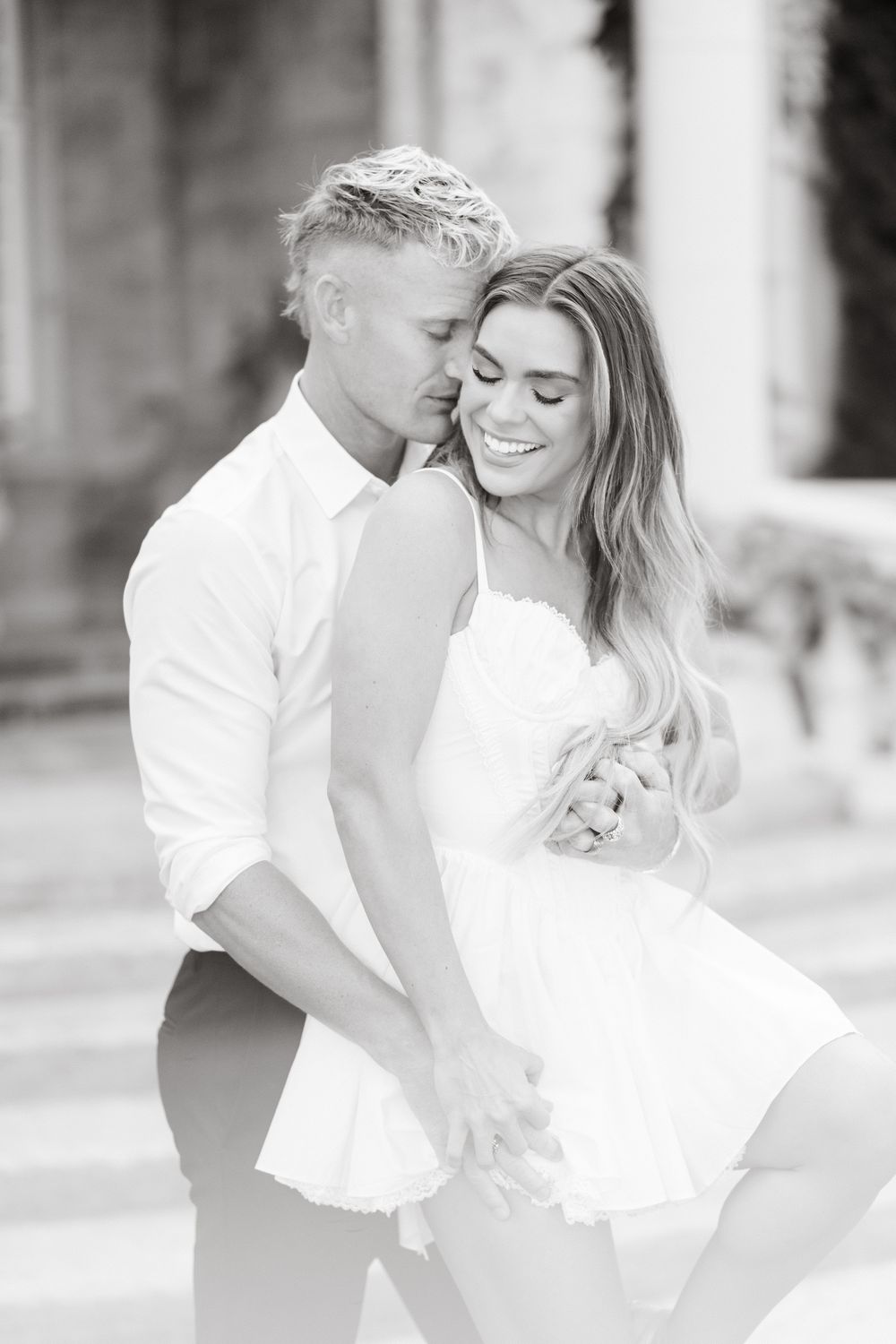 Black and white romantic photos showing a couple dancing together in white formal attire.