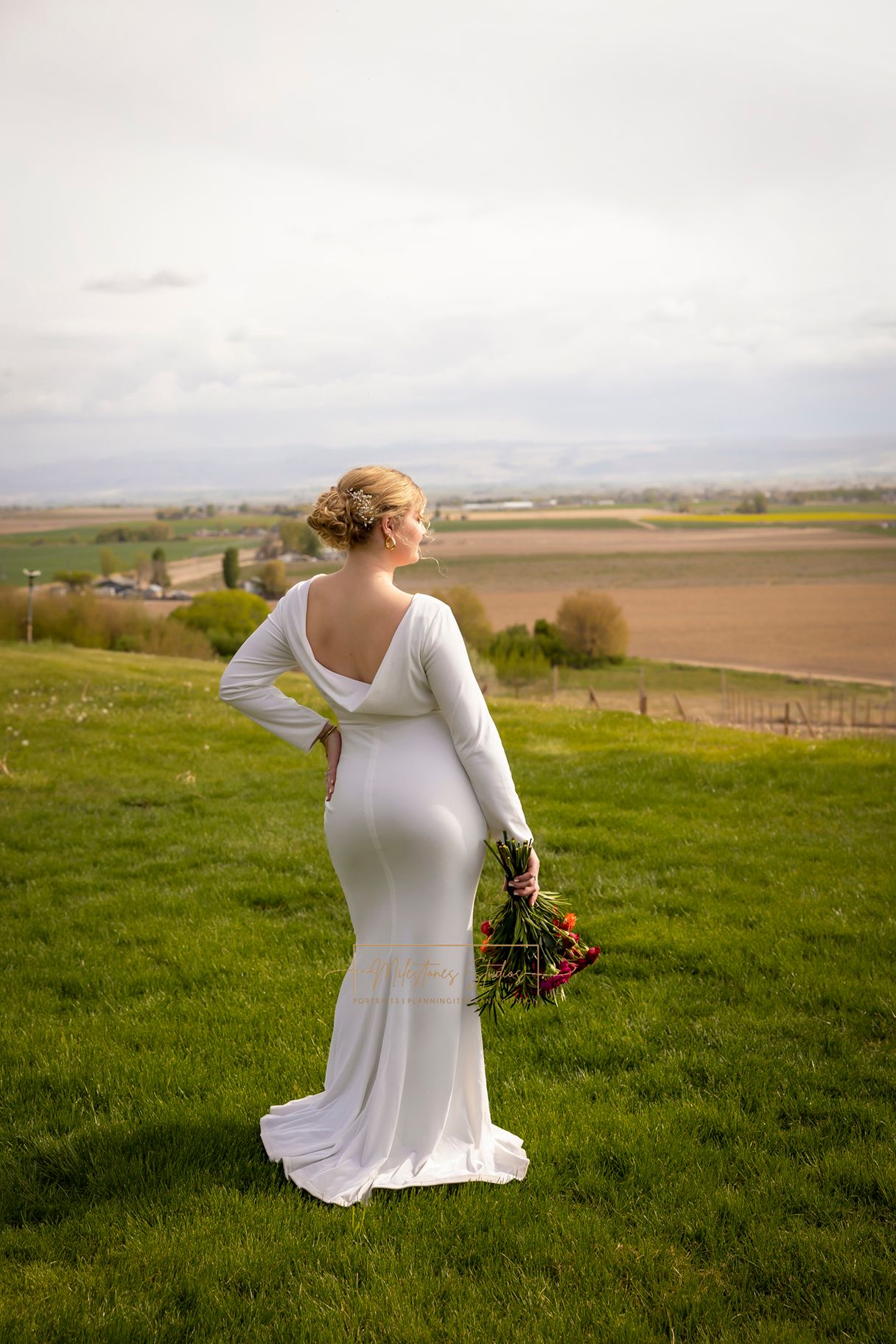portrait of bride from behind in fitted white gown with draping white fabric showing back