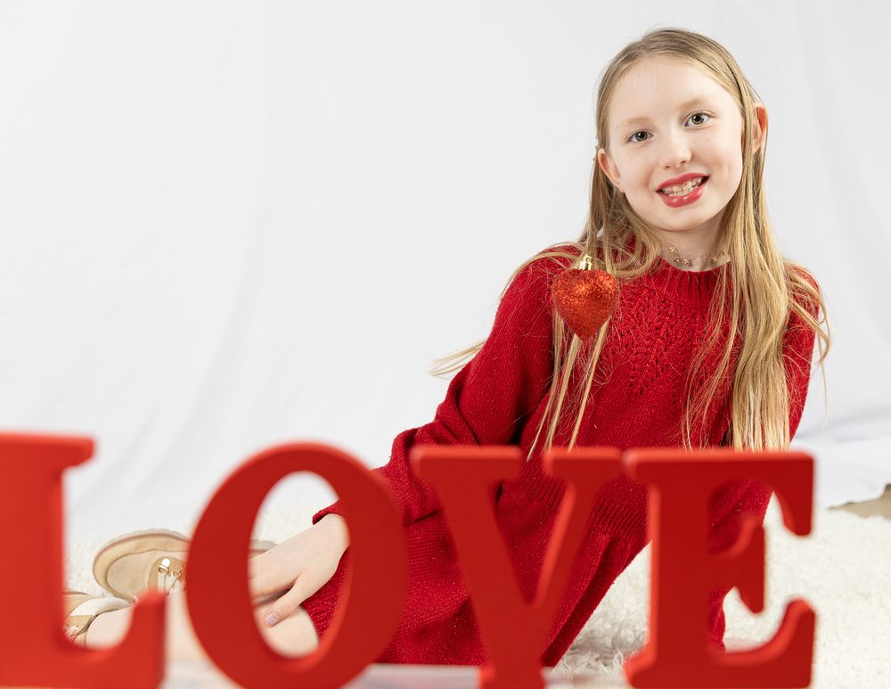 A decorative red LOVE sign in large letters against a white background with someone in a red sweater.
