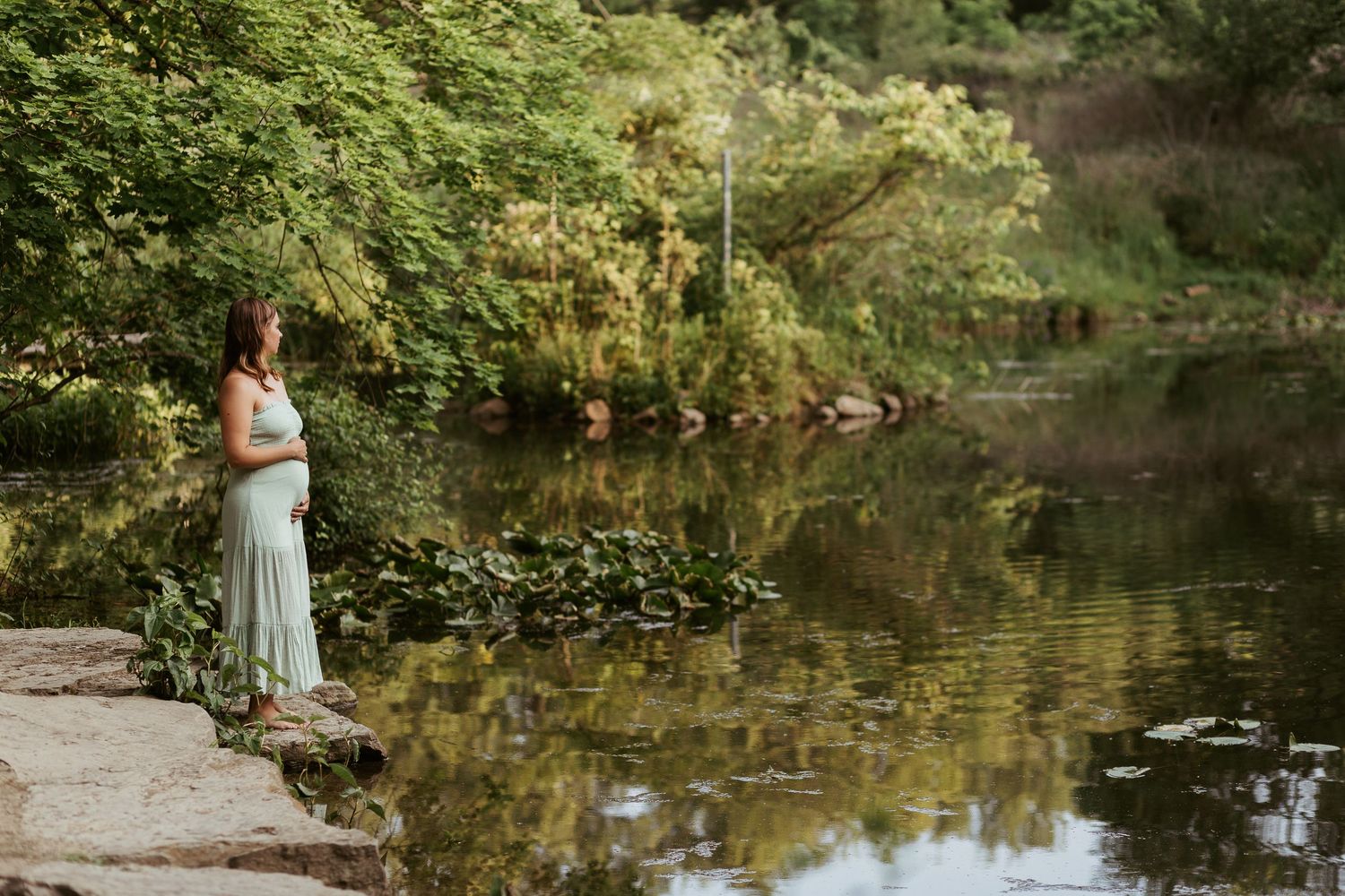 maternity photos in pittsburgh pennsylvania by ash coniglio photography, woman stands looking out at lily filled pond