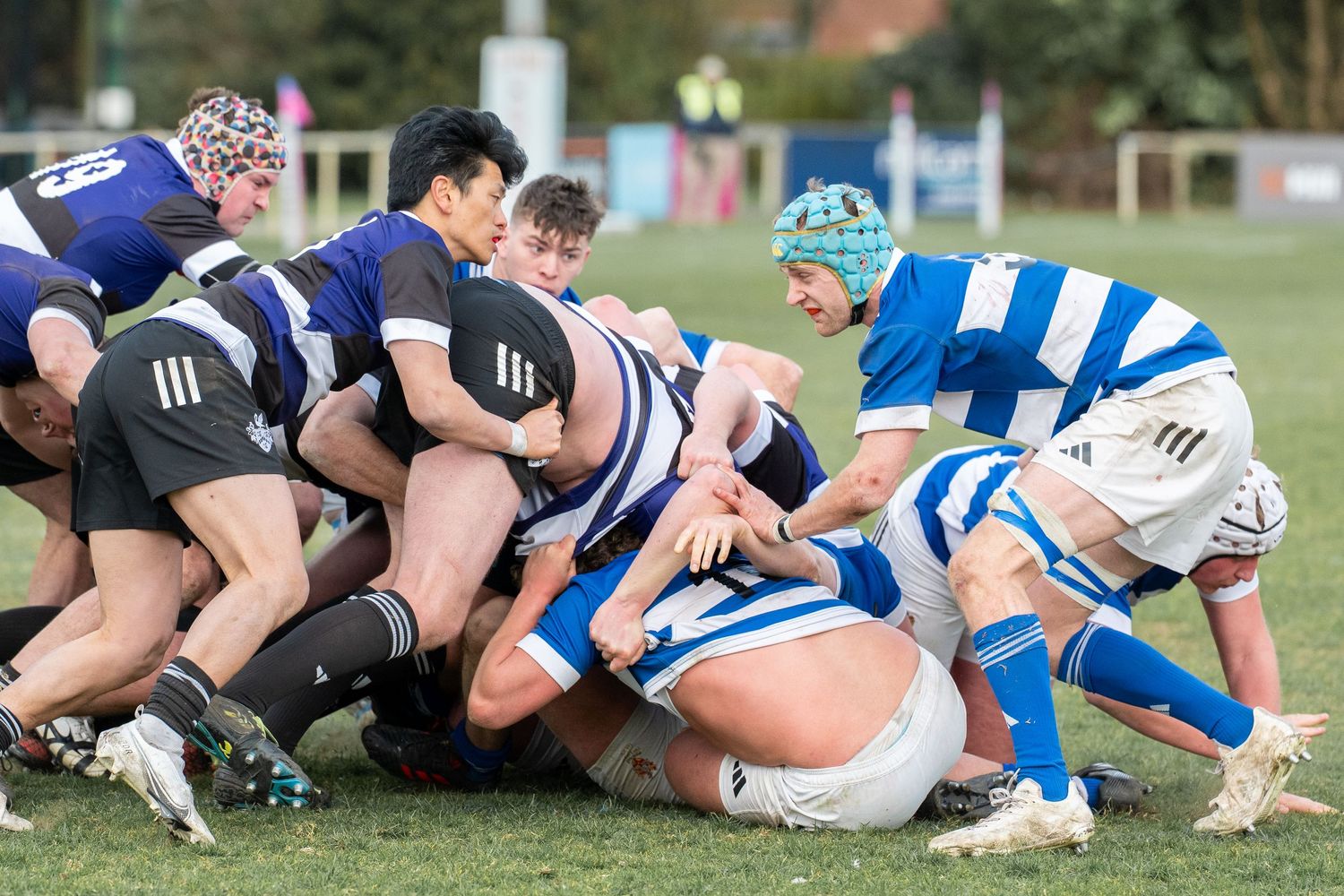 Rugby players from opposing teams locked in a scrum formation during an intense match on grass field.