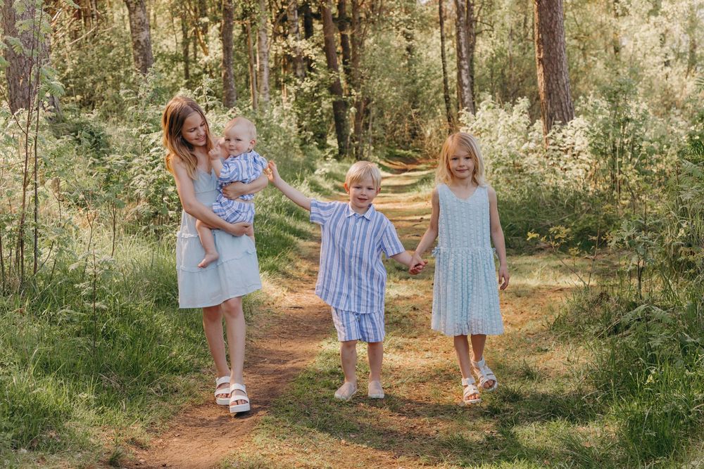 Family walking together on forest path wearing coordinating blue and white outfits.