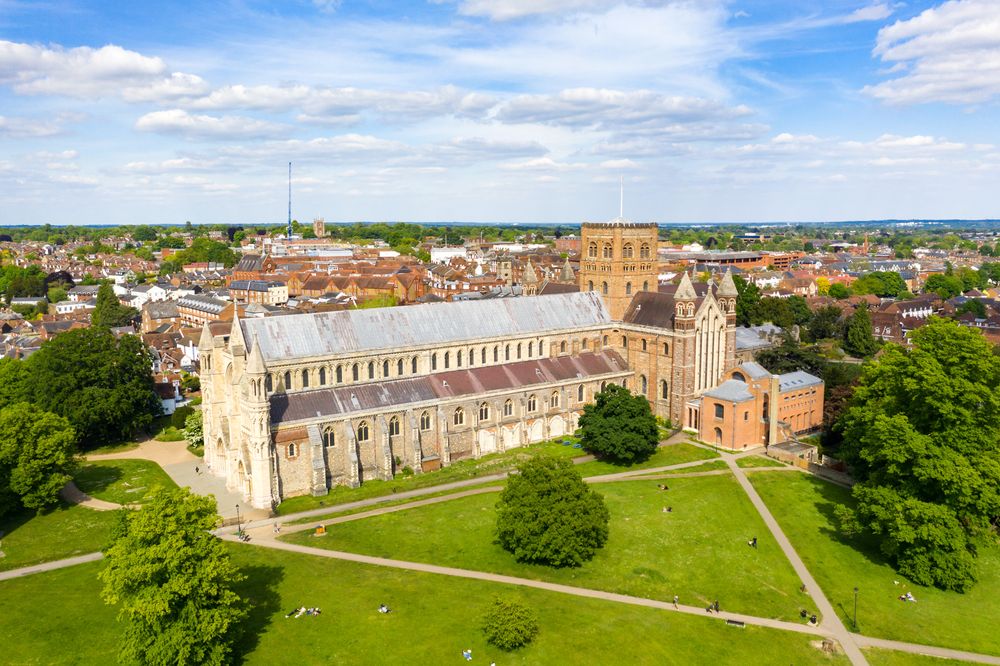 Aerial view of St Albans Cathedral with its Norman architecture and surrounding green lawns on a sunny summer day.