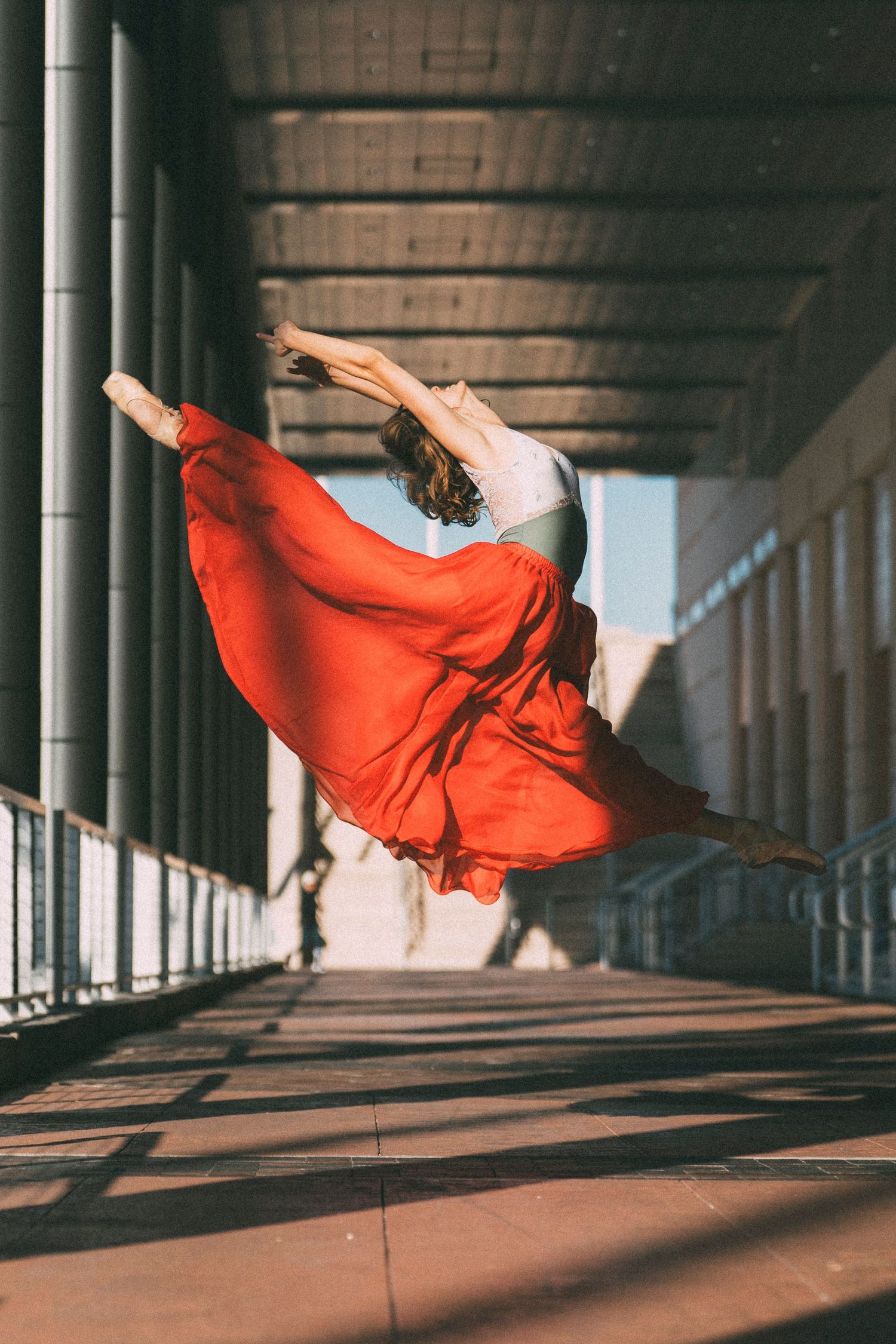tampa ballet dance photography with ballerina in red skirt and leotard in pointe shoes leaping in the air