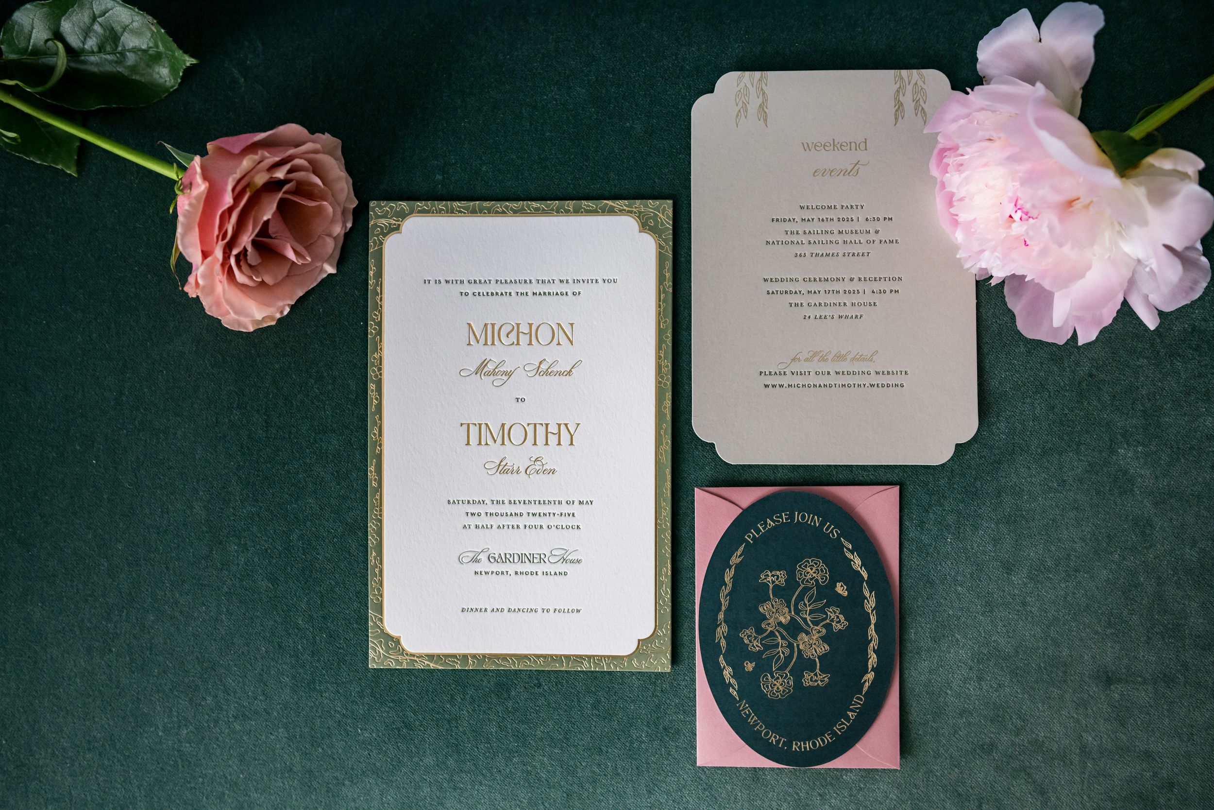 Elegant wedding invitation suite featuring pink flowers and gold accents on dark green marble background.