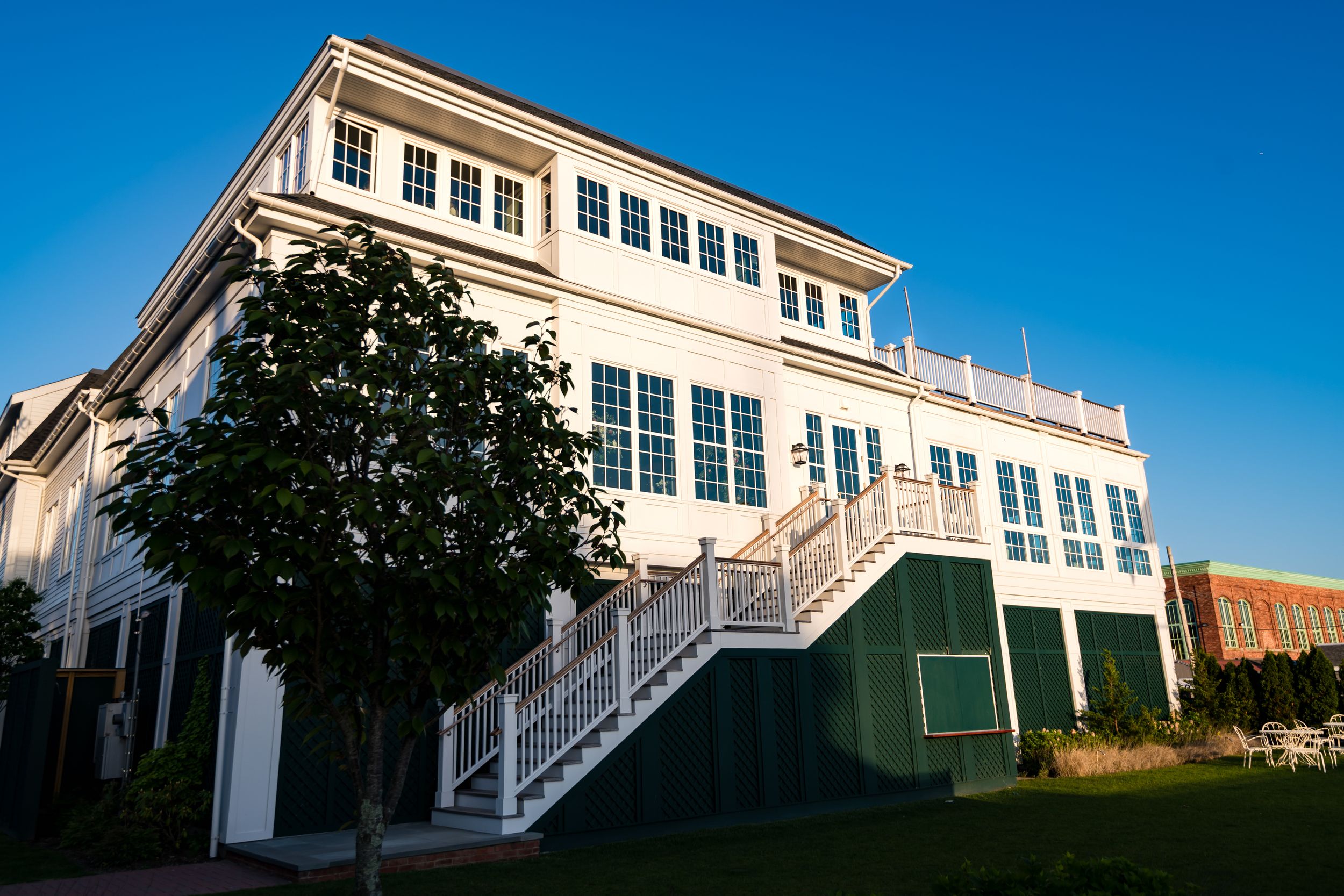 Modern white coastal homes with large windows and exterior staircases line up against a vibrant blue sky backdrop.