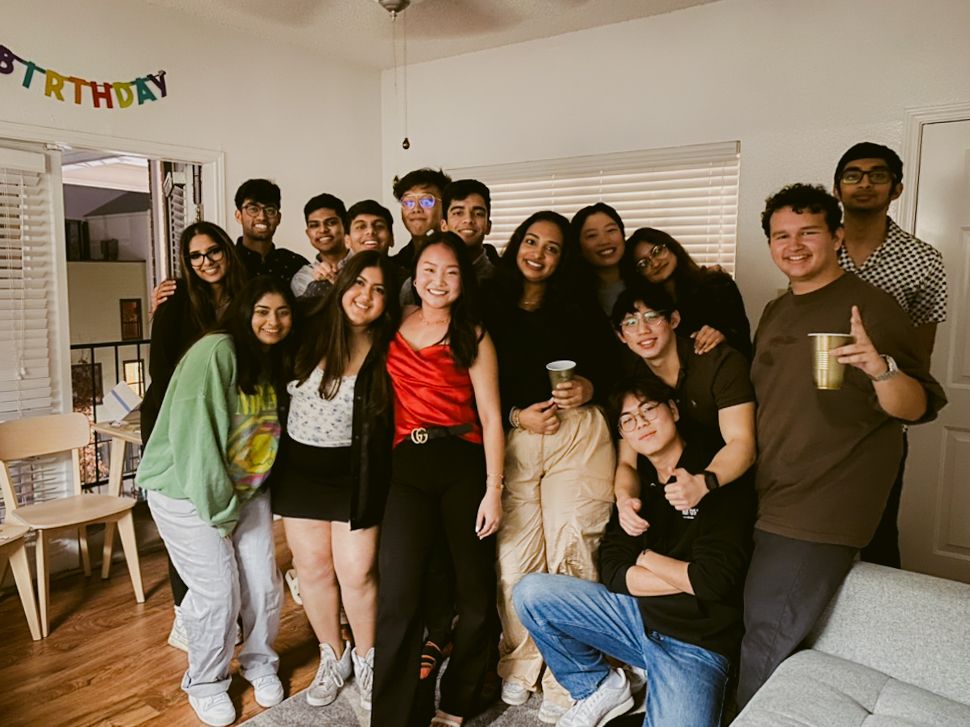 Group of people gathered together at a birthday party in a home living room with birthday banner decoration.