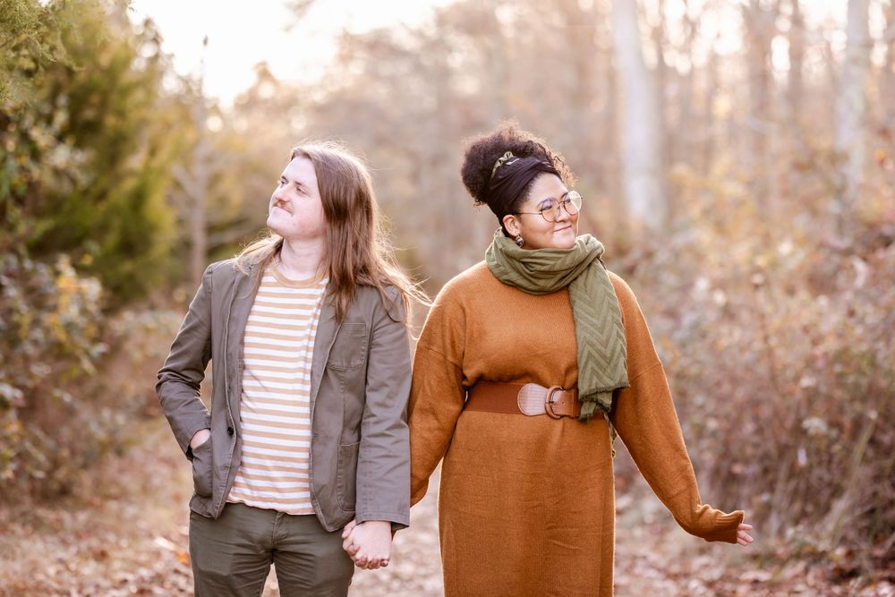 Two people walking together on an autumn path wearing cozy seasonal outfits.