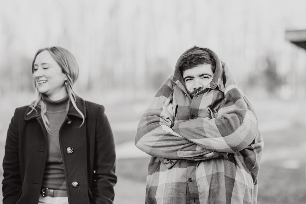 Two people laughing together outdoors in black and white photography.
