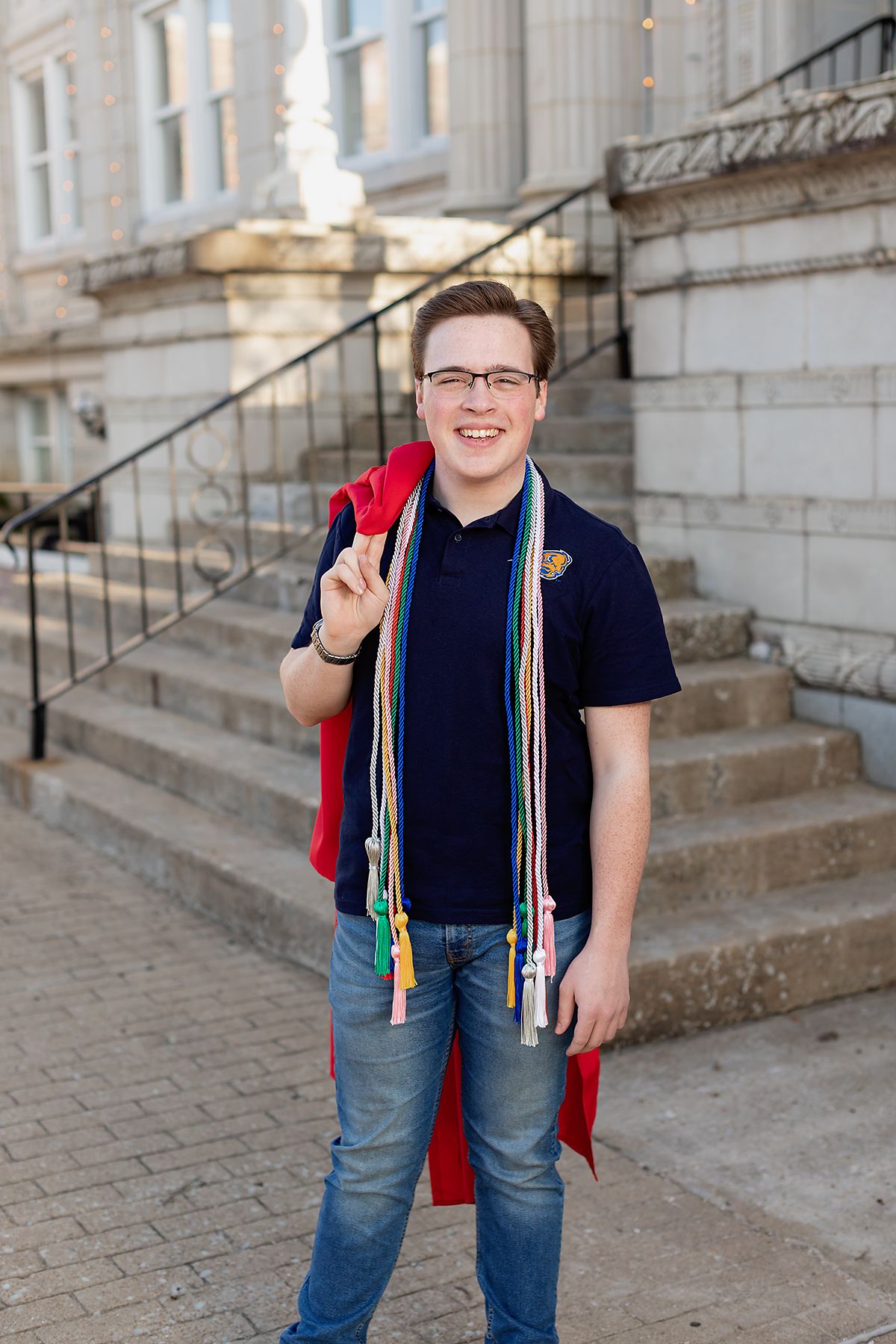 Senior pictures by MegMc Photography of a male teen wearing his college choice shirt with graduation gown over his shoulder in Jackson, TN.