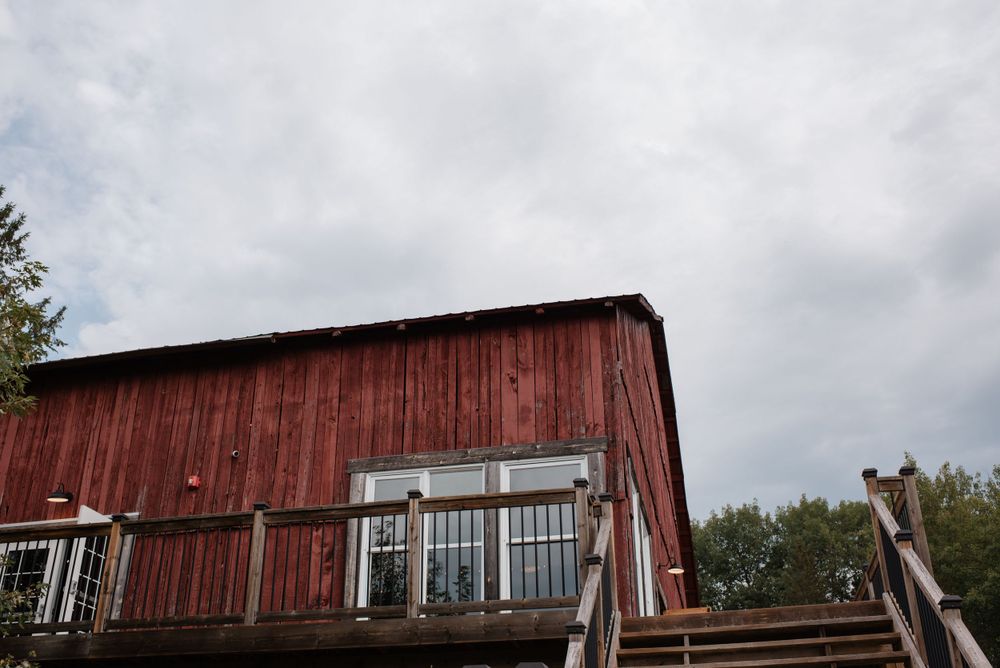 Looking up at a rustic red barn structure with a cloudy sky overhead and wooden railings in the foreground.