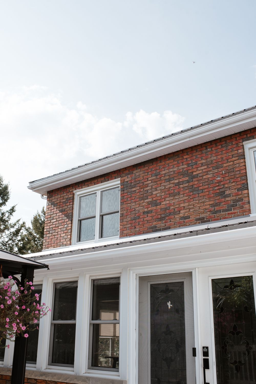 Exterior view of a classic brick house with white trim windows and a dark front door.