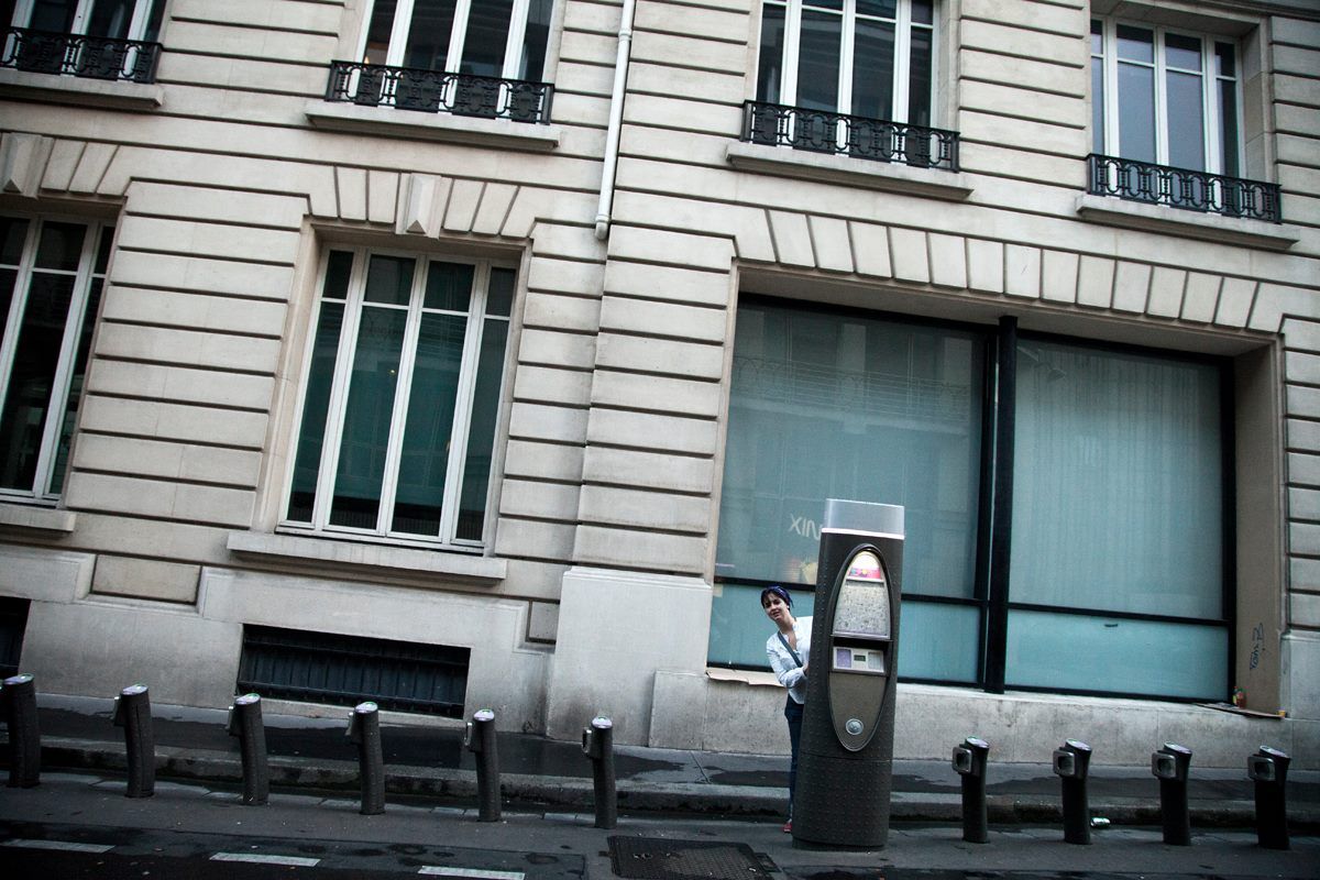 Classic Parisian building facade with shuttered windows and bike parking posts.
