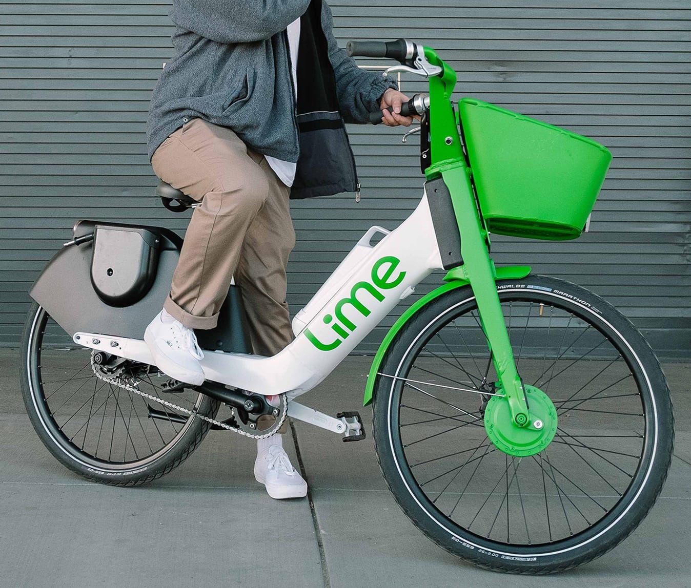 Close-up of a bright green Lime rental bike with distinctive design features against a gray background.