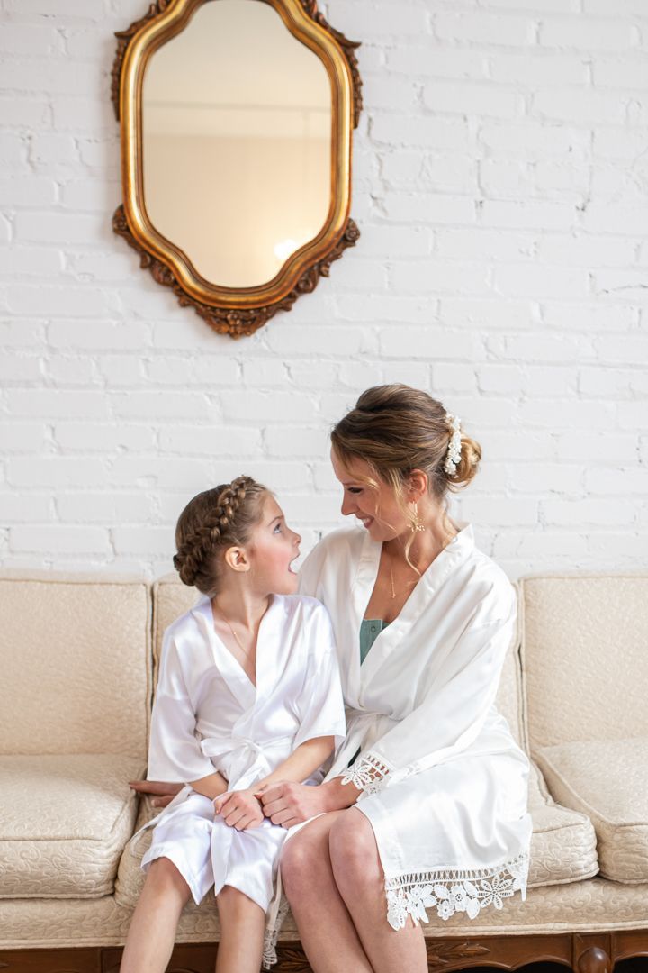 Wedding preparation moment shared on cream couch beneath ornate gold mirror.