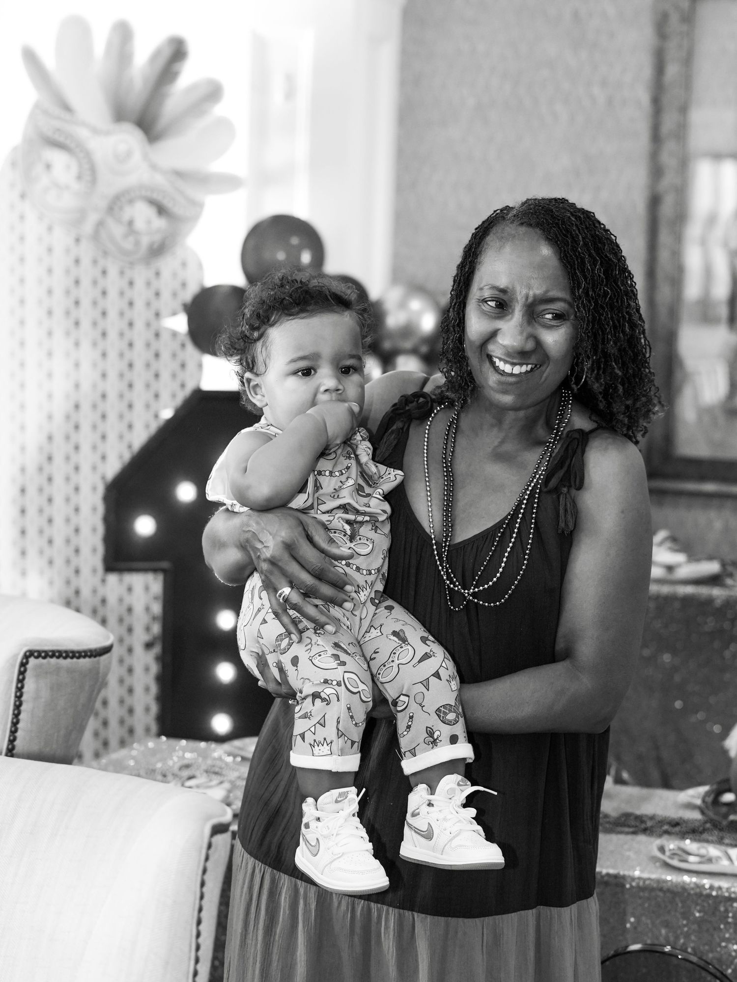 Black and white portrait at a celebration event with decorative lighting in background.