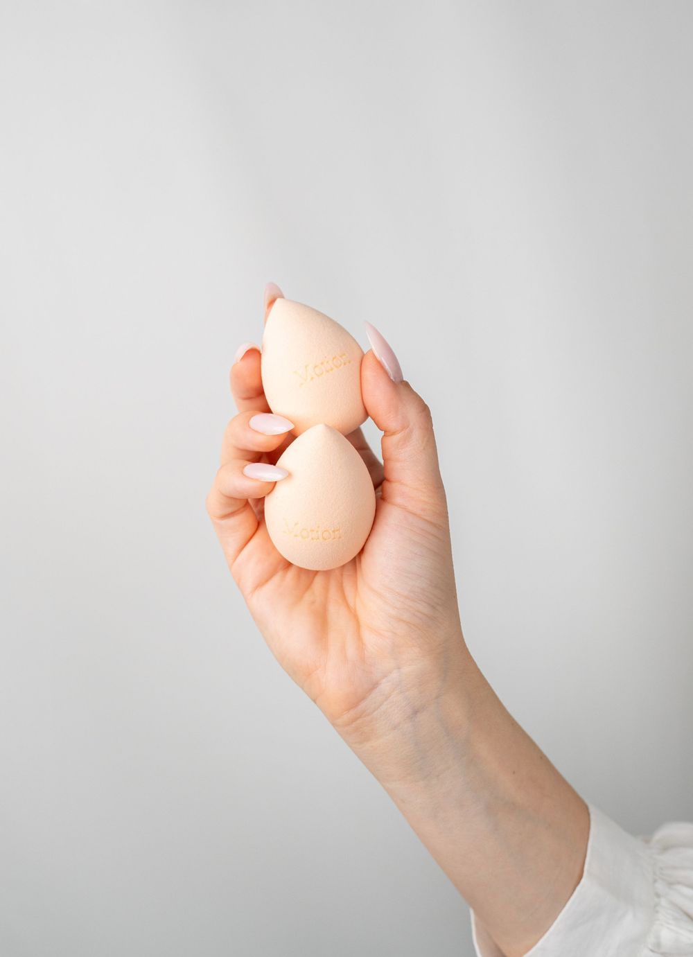 Beauty blender sponges being displayed against minimalist gray backdrop.