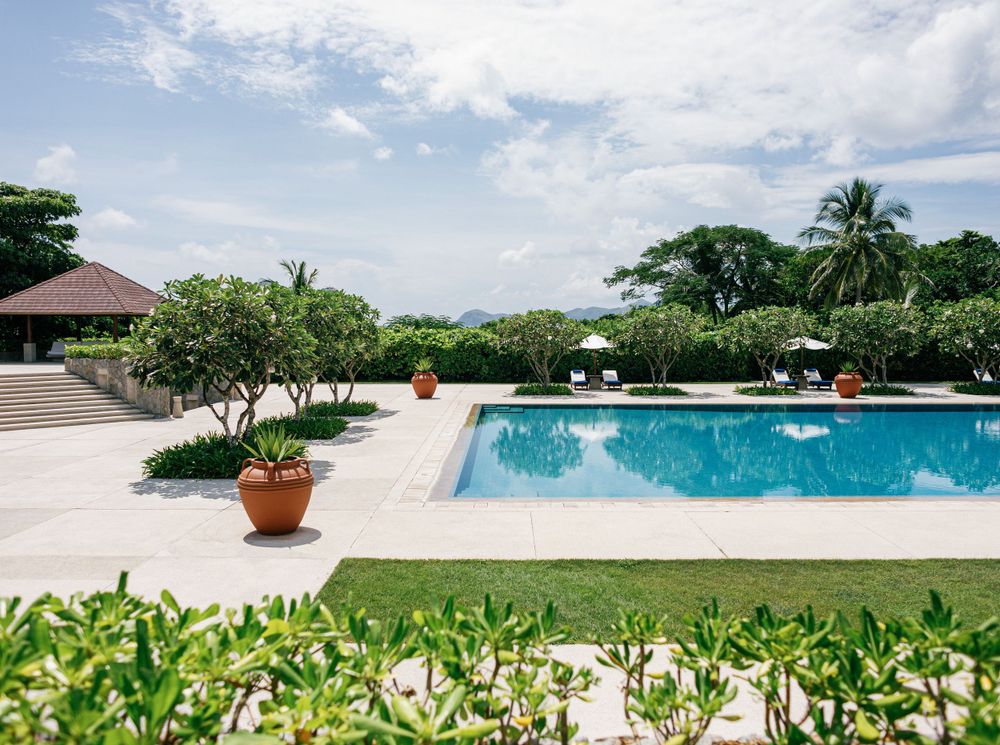 A serene swimming pool surrounded by lush greenery at Aman resort, Amanpulo, Philippines.