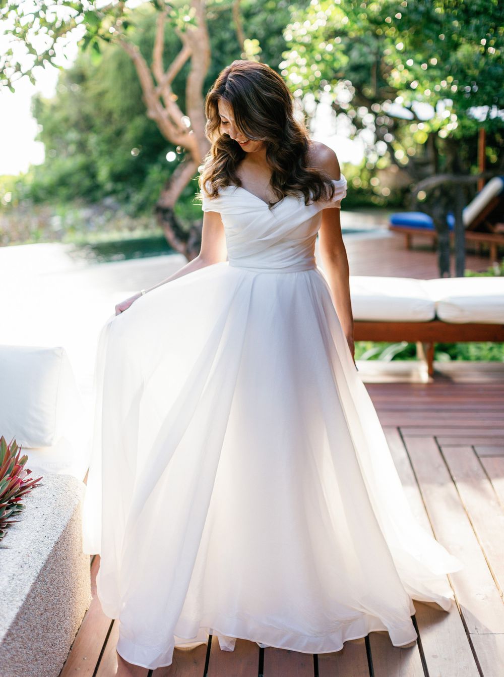 A bride in a white wedding dress standing on a wooden deck at Aman resort in Amanpulo, Philippines.