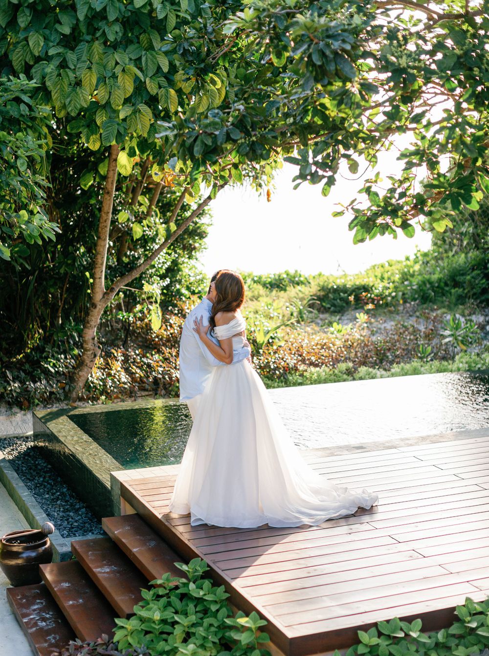 Bride and groom hugging by pool at Aman resort in Amanpulo, Philippines.