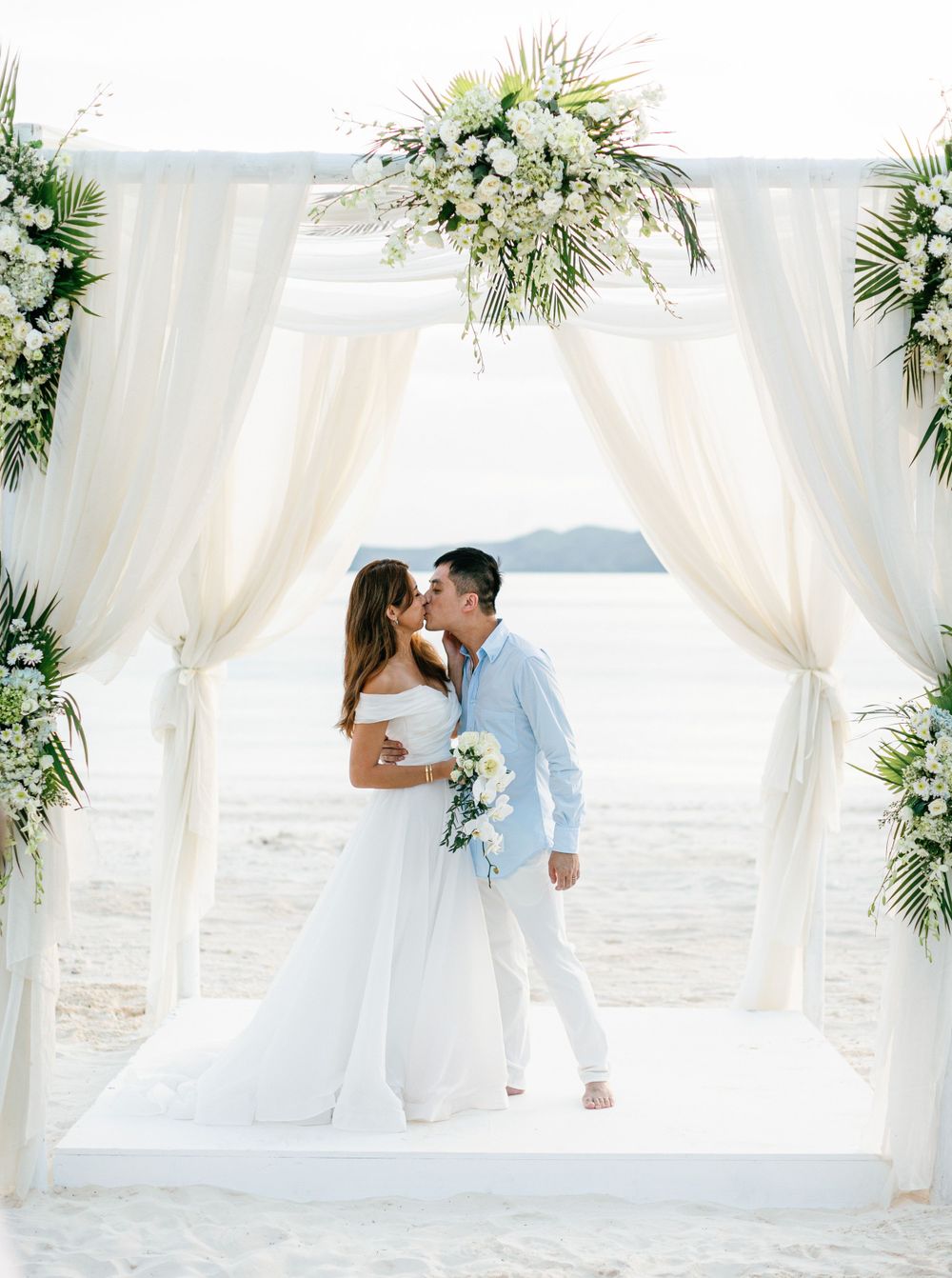 Romantic beach wedding at Amanpulo when bride and groom kiss, Philippines.