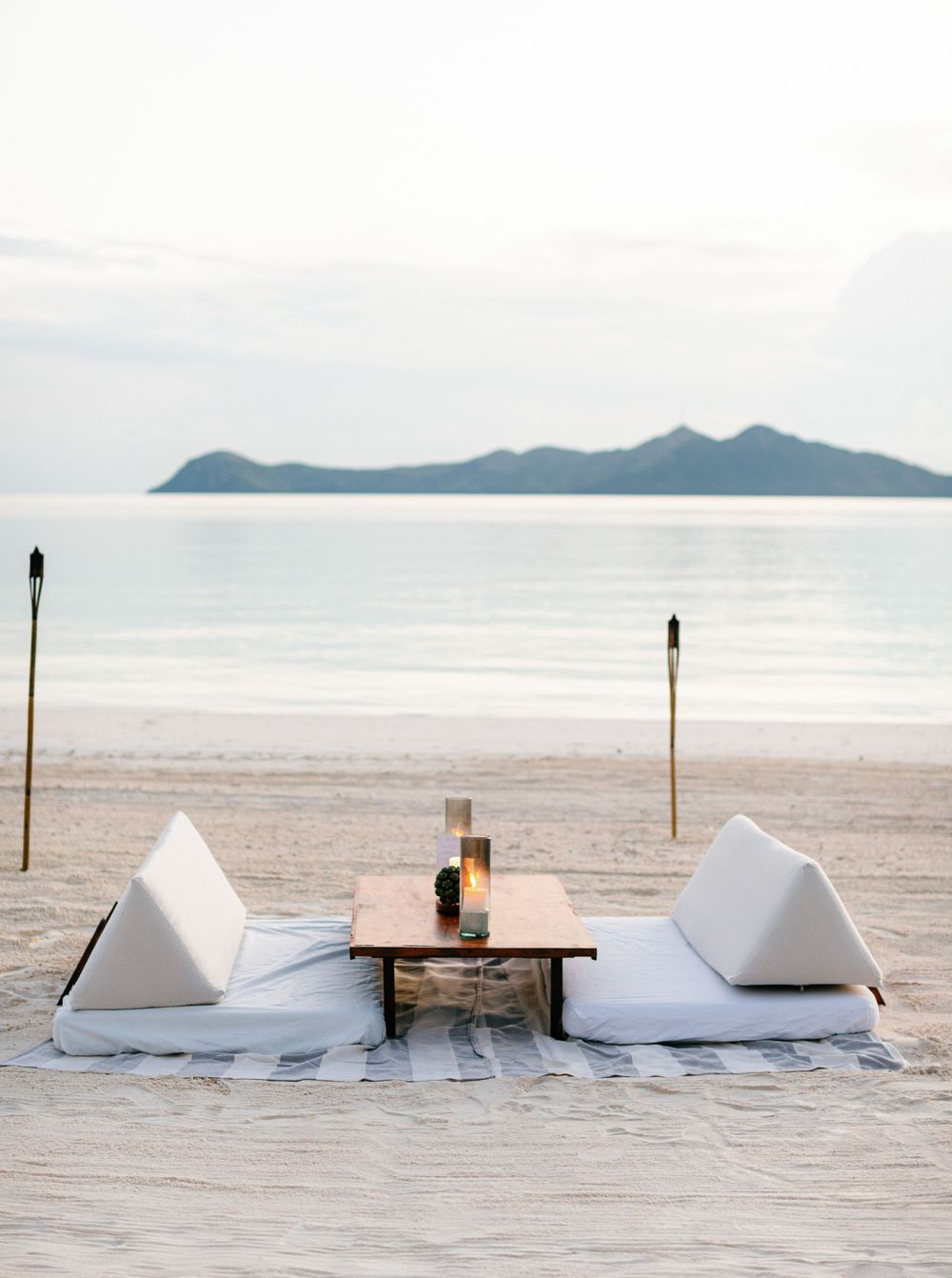Tranquil beach scene with white sand and sofas, a lovely setting for a wedding cocktail at Aman resort in Amanpulo,