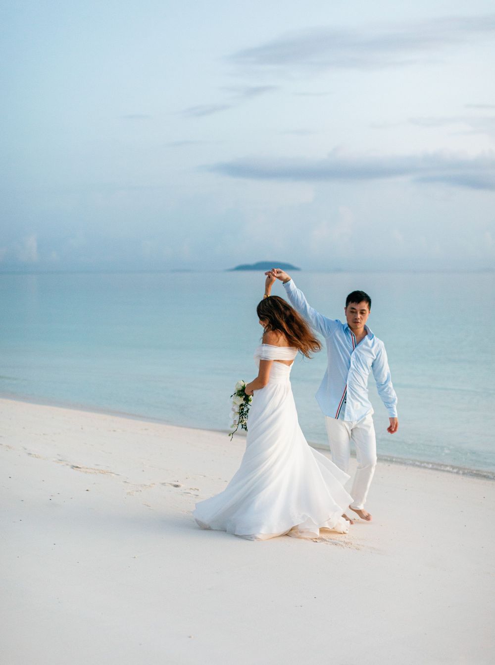 Wedding couple enjoying a romantic walk on Amanpulo beach, Philippines.