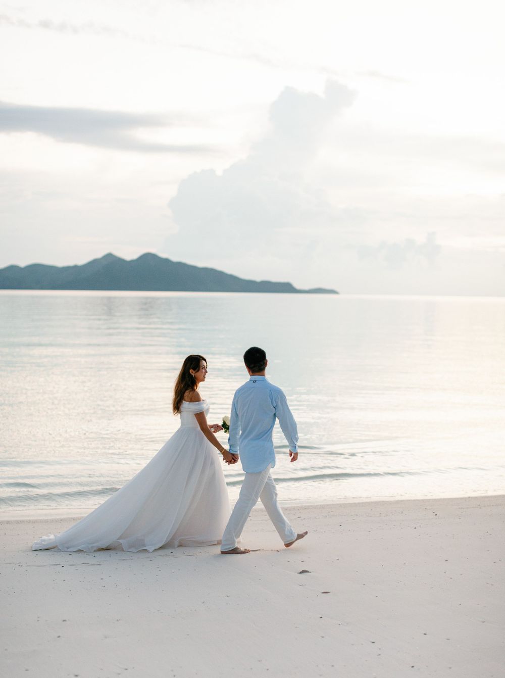 Newlyweds strolling on Amanpulo beach, Philippines, enjoying their romantic walk.