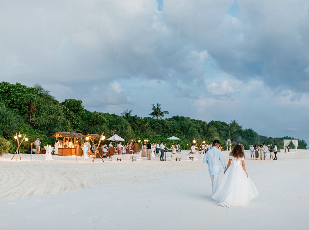 Newlyweds strolling on the sandy beach in Amanpulo, Philippines.