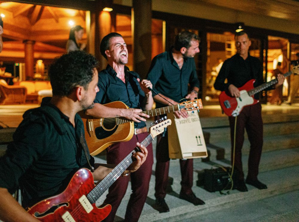Group of men performing music with guitars and singing at Amanpulo, Philippines wedding.