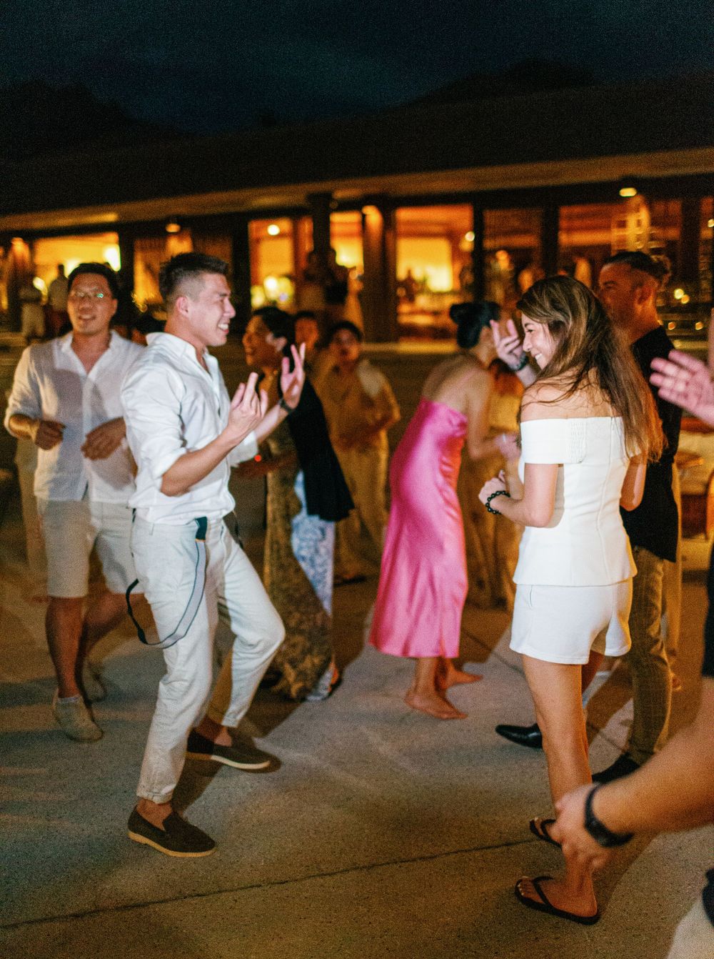 Festive wedding gathering in Amanpulo, Philippines, featuring a group of people joyfully dancing.