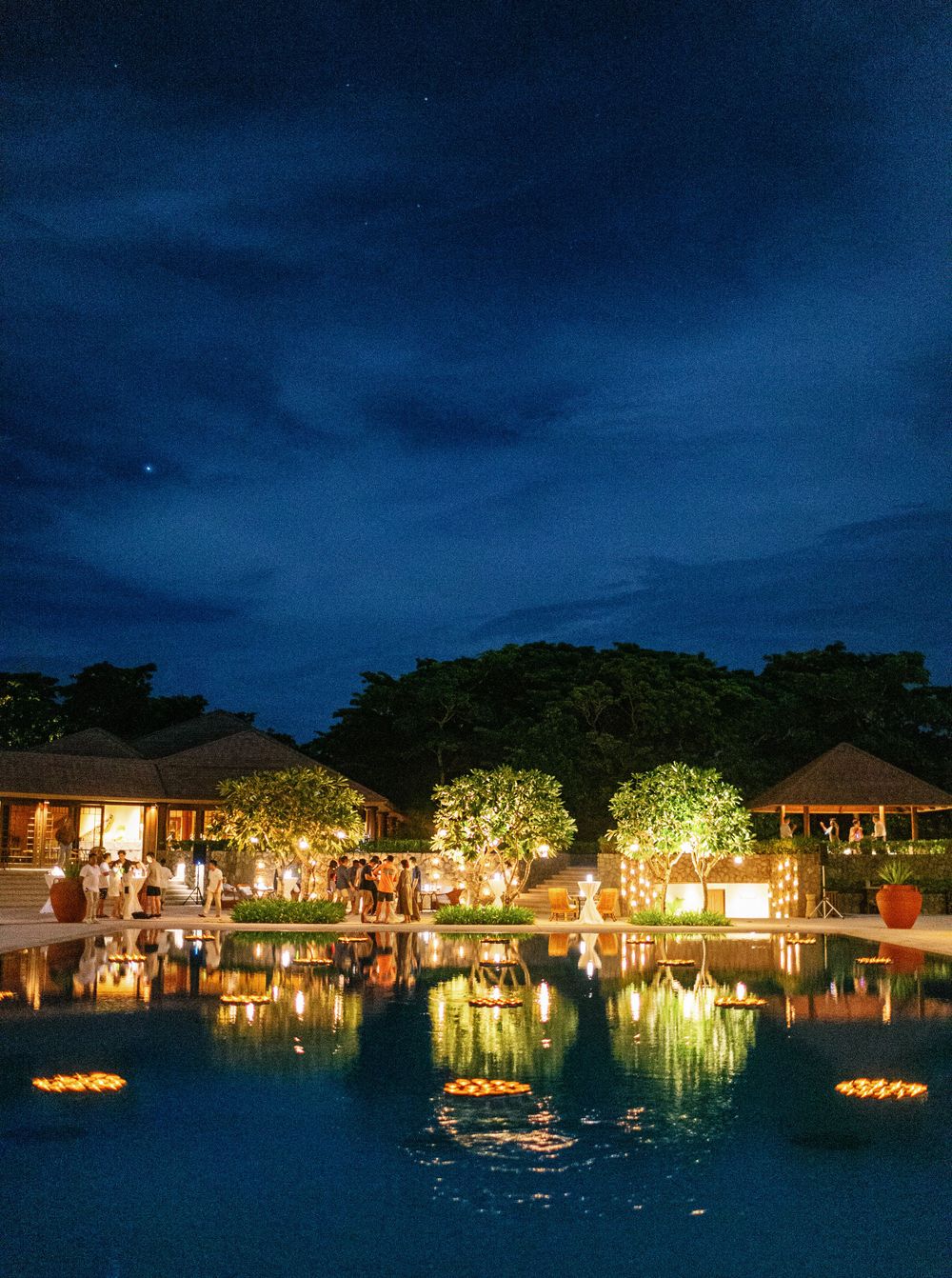 Nighttime pool scene with glowing lights creating a magical atmosphere for a wedding celebration in Amanpulo, Philippine
