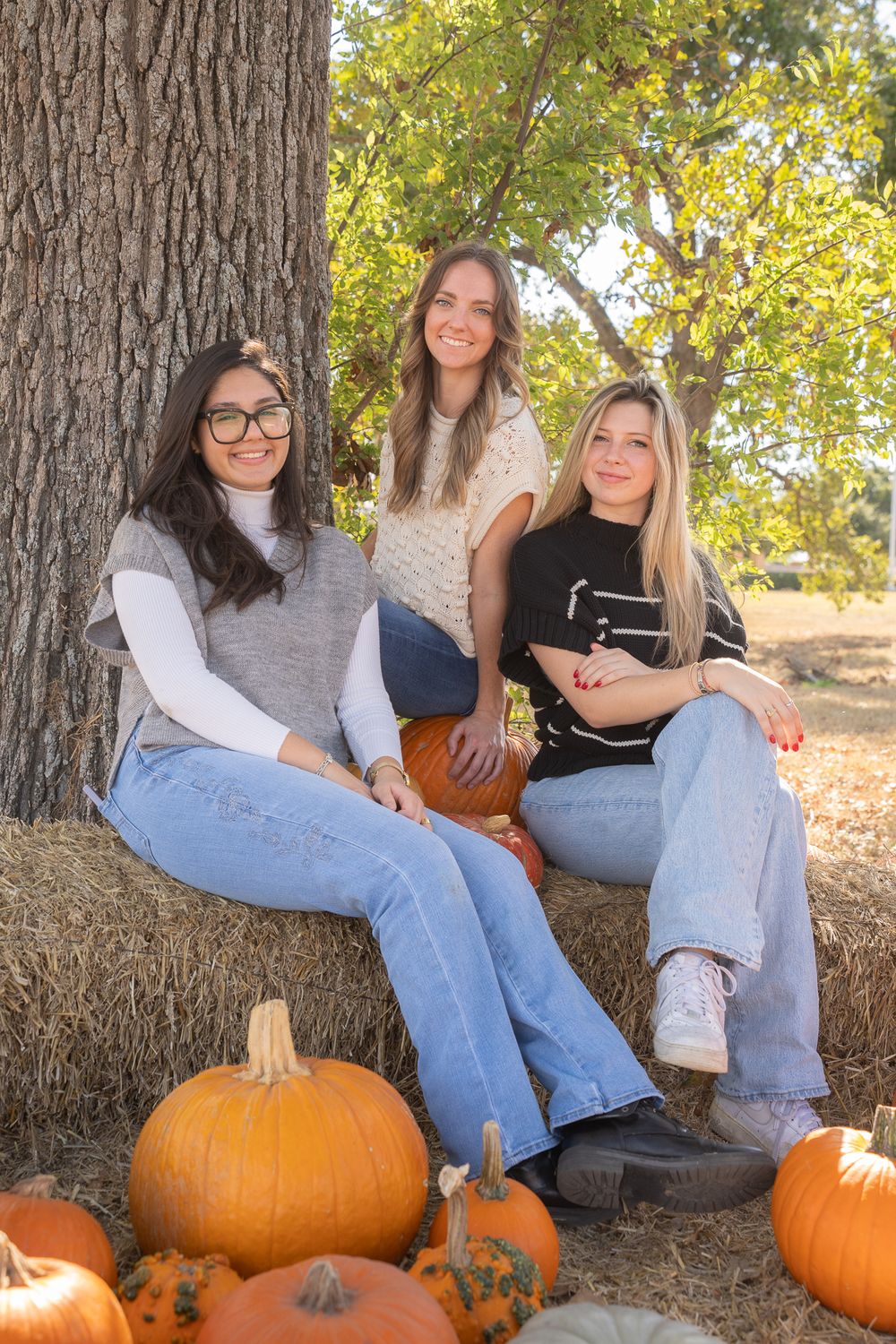 Girls enjoying time in a pumpkin patch in College Station, Texas, capturing autumn fun and laughter.