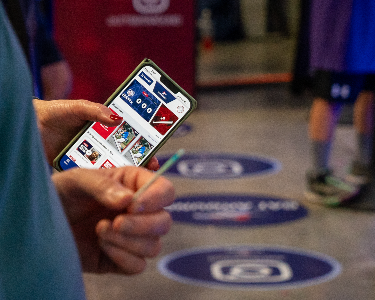 Hand holding smartphone displaying social media content with blue circular floor markers visible.