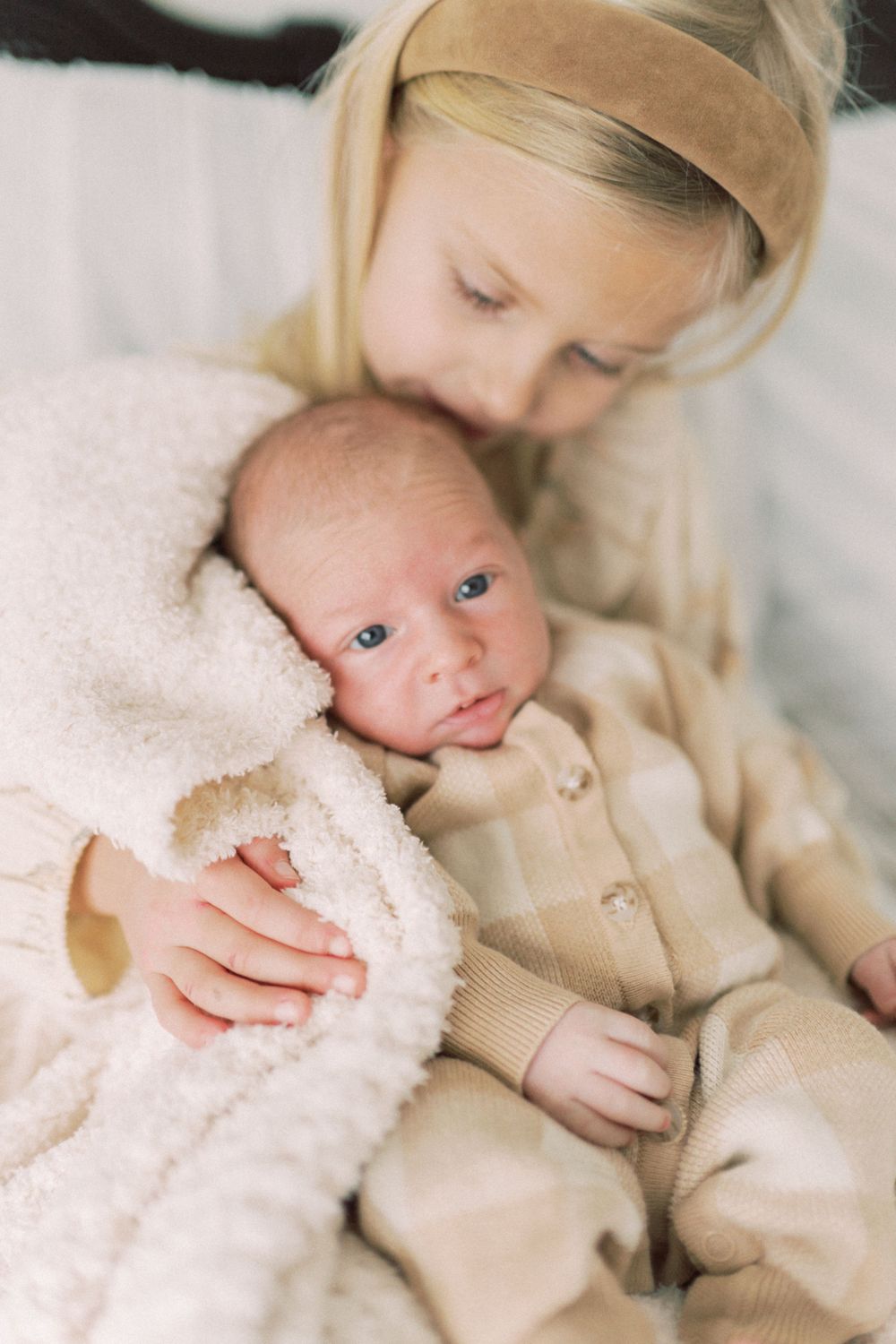 A tender moment between parent and baby wrapped in cozy cream-colored fabrics.